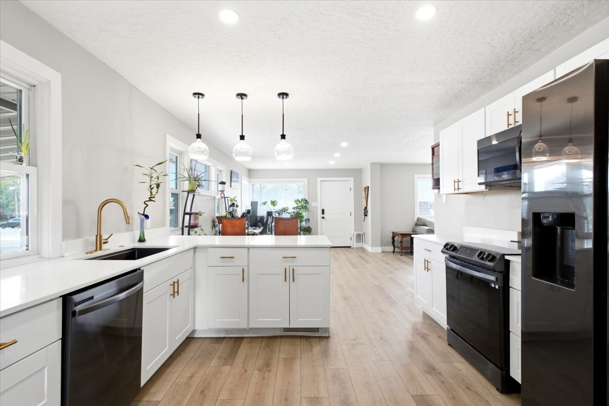 Spacious, updated kitchen features new quartz countertops, large single-basin sink, black stainless steel appliances, abundant cabinetry with brass cabinet hardware, and pantry storage!