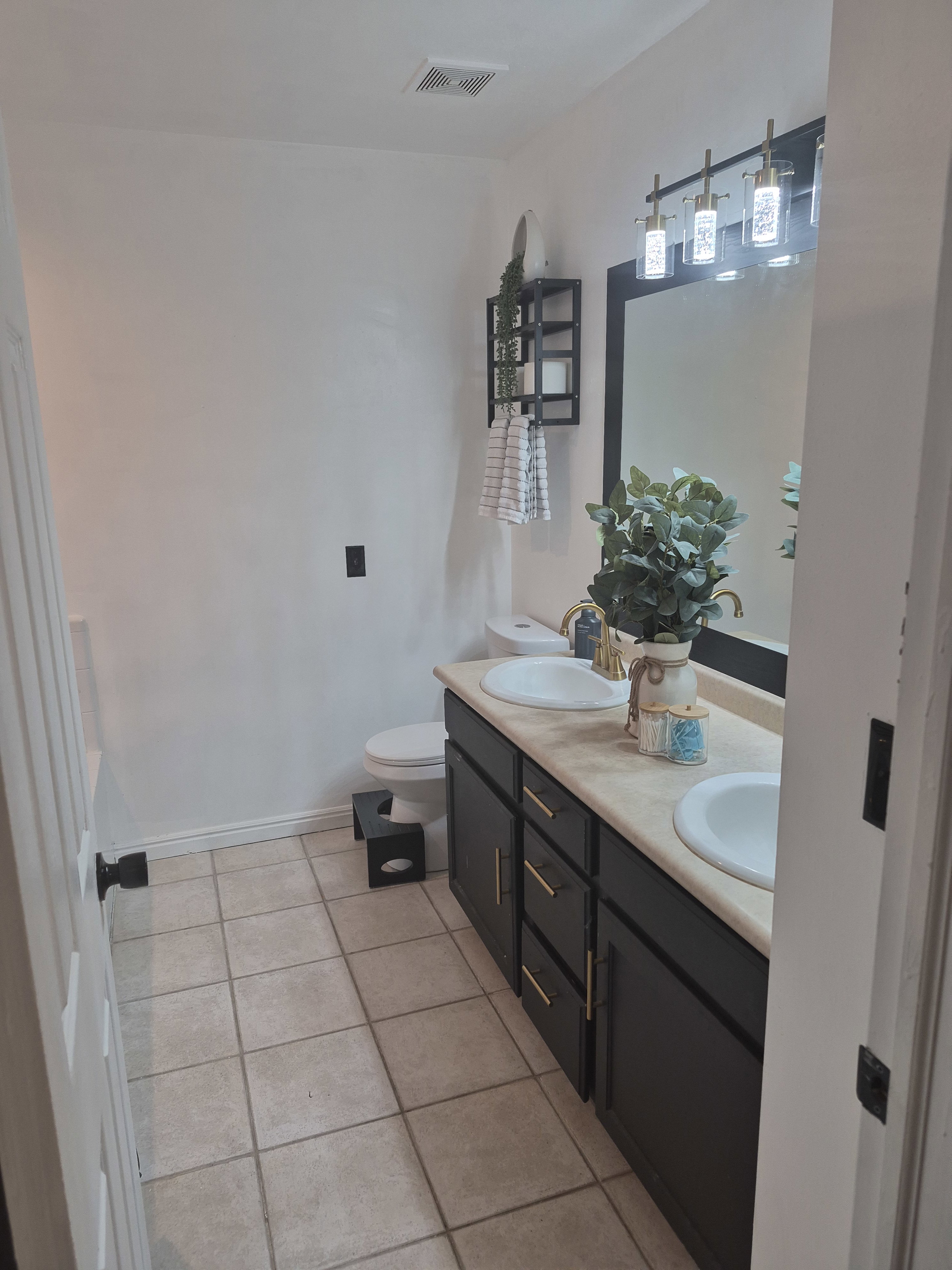 Dual vanity with black cabinetry, gold-finish hardware, and integrated sinks