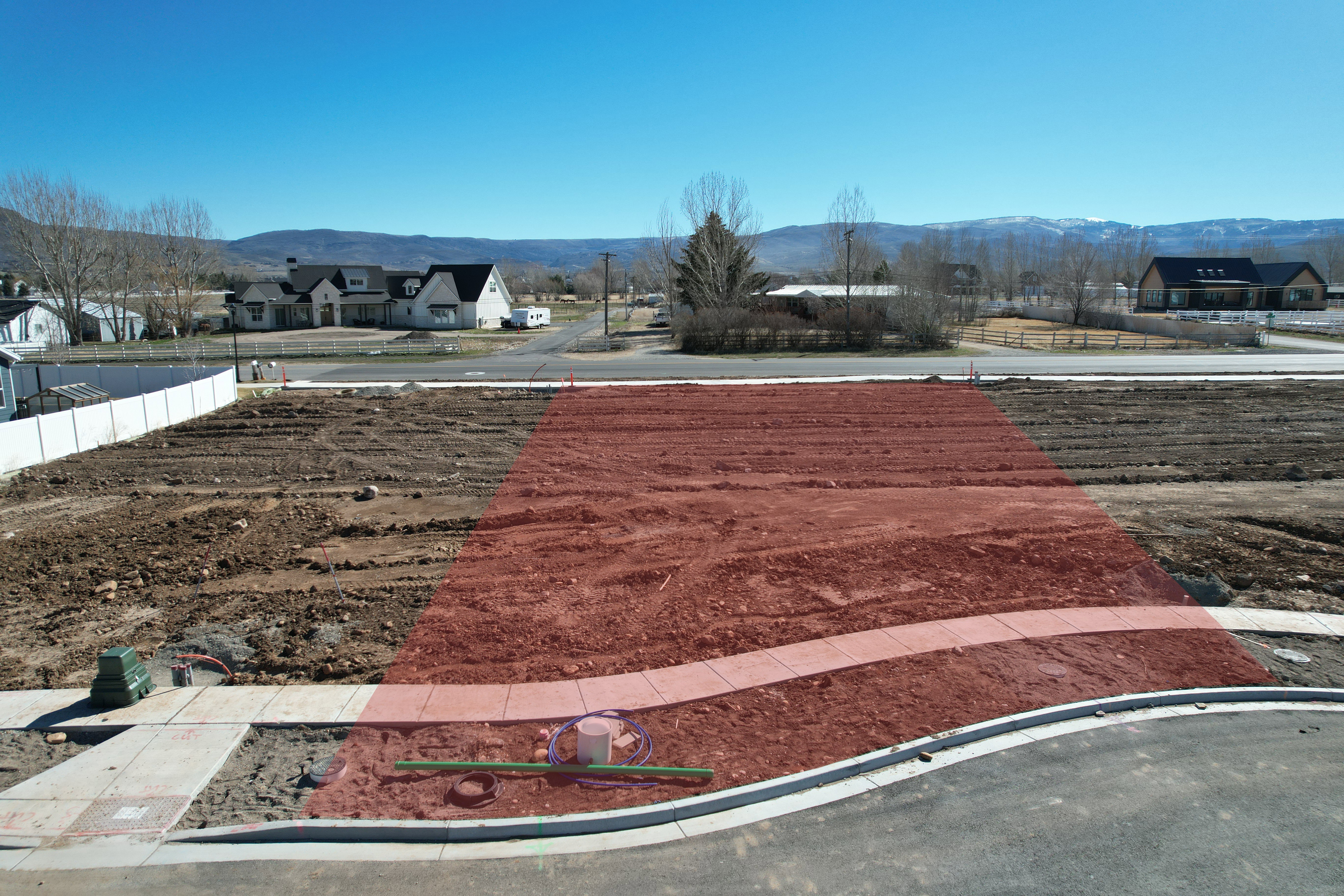 Cleared building lot with established curb and sidewalk