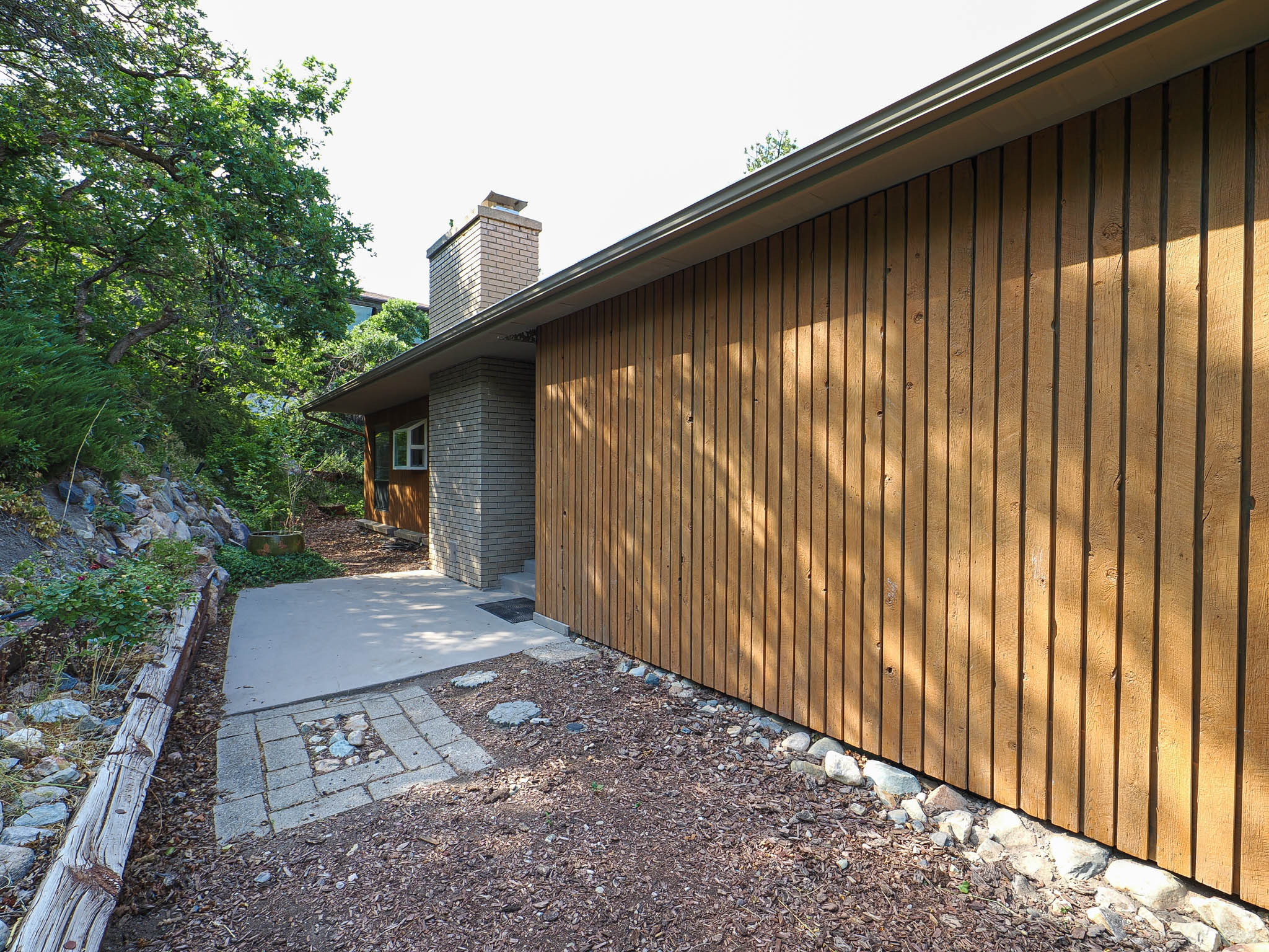 Vertical wood siding exterior with a brick chimney accent