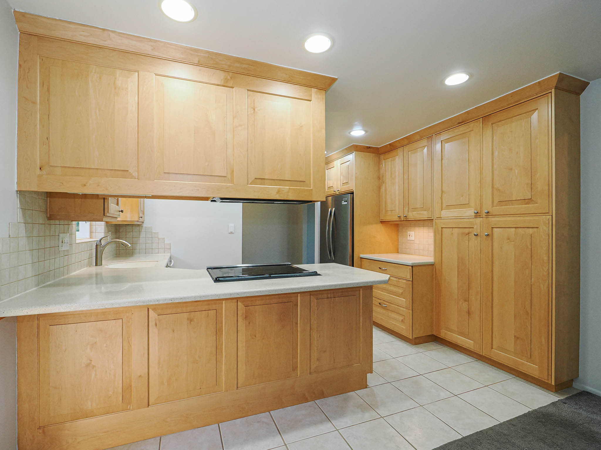 Kitchen featuring extensive light wood cabinetry, recessed lighting, tile flooring, a built-in cooktop, and light-toned countertops