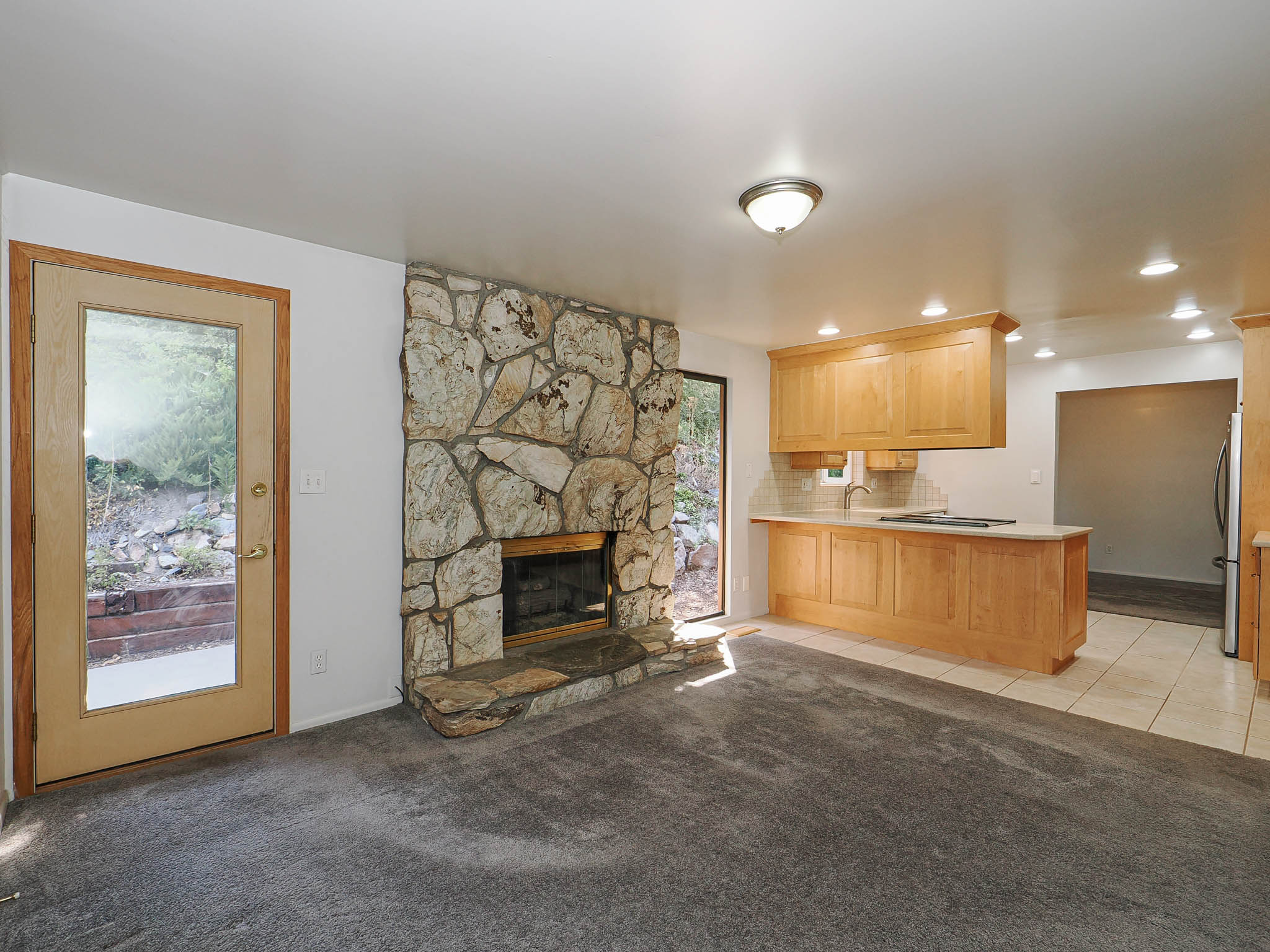 Living area featuring a stone-clad fireplace and a glass-paneled door