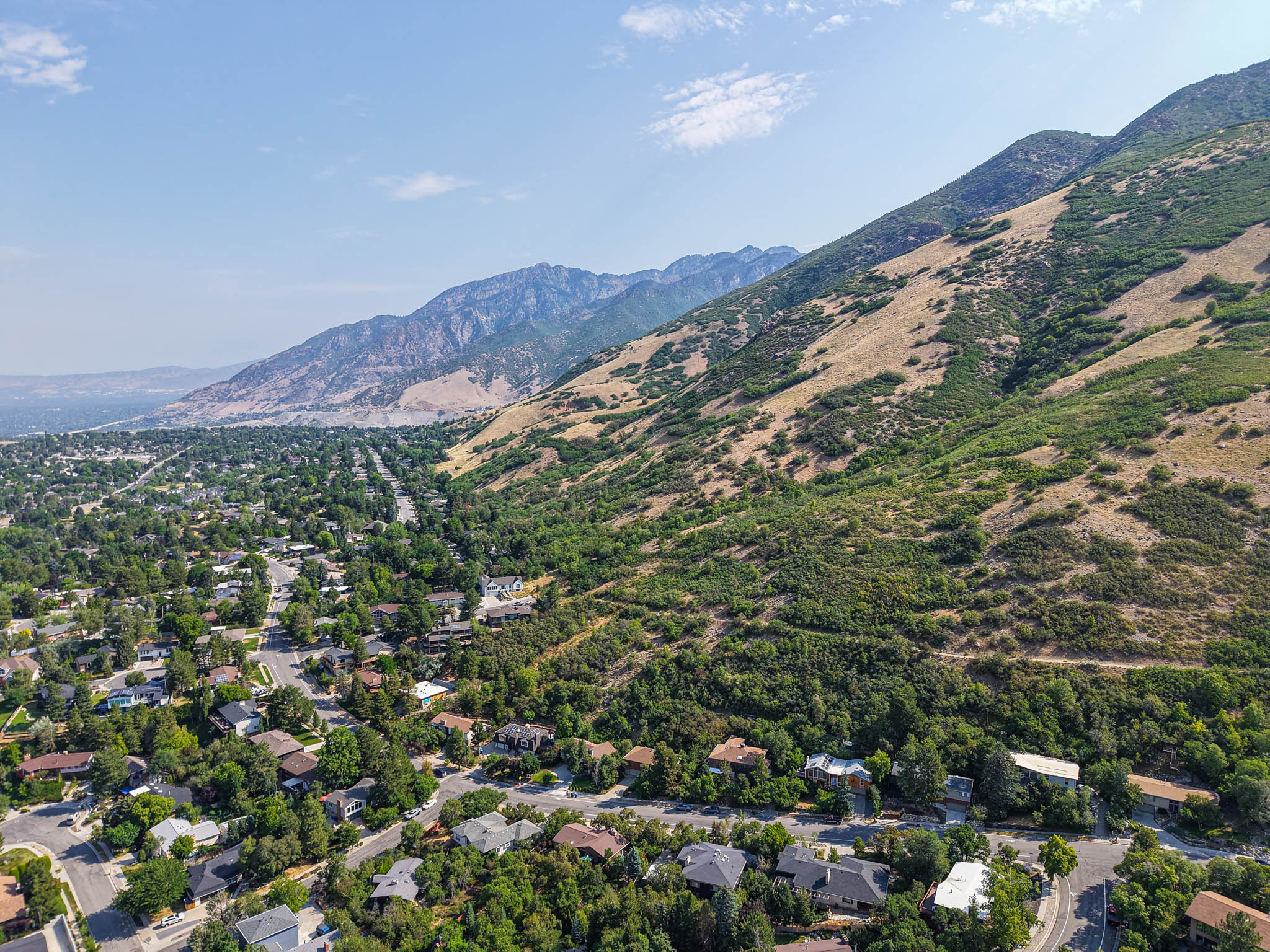 Expansive aerial perspective showcasing a residential area nestled at the base of a verdant mountain range