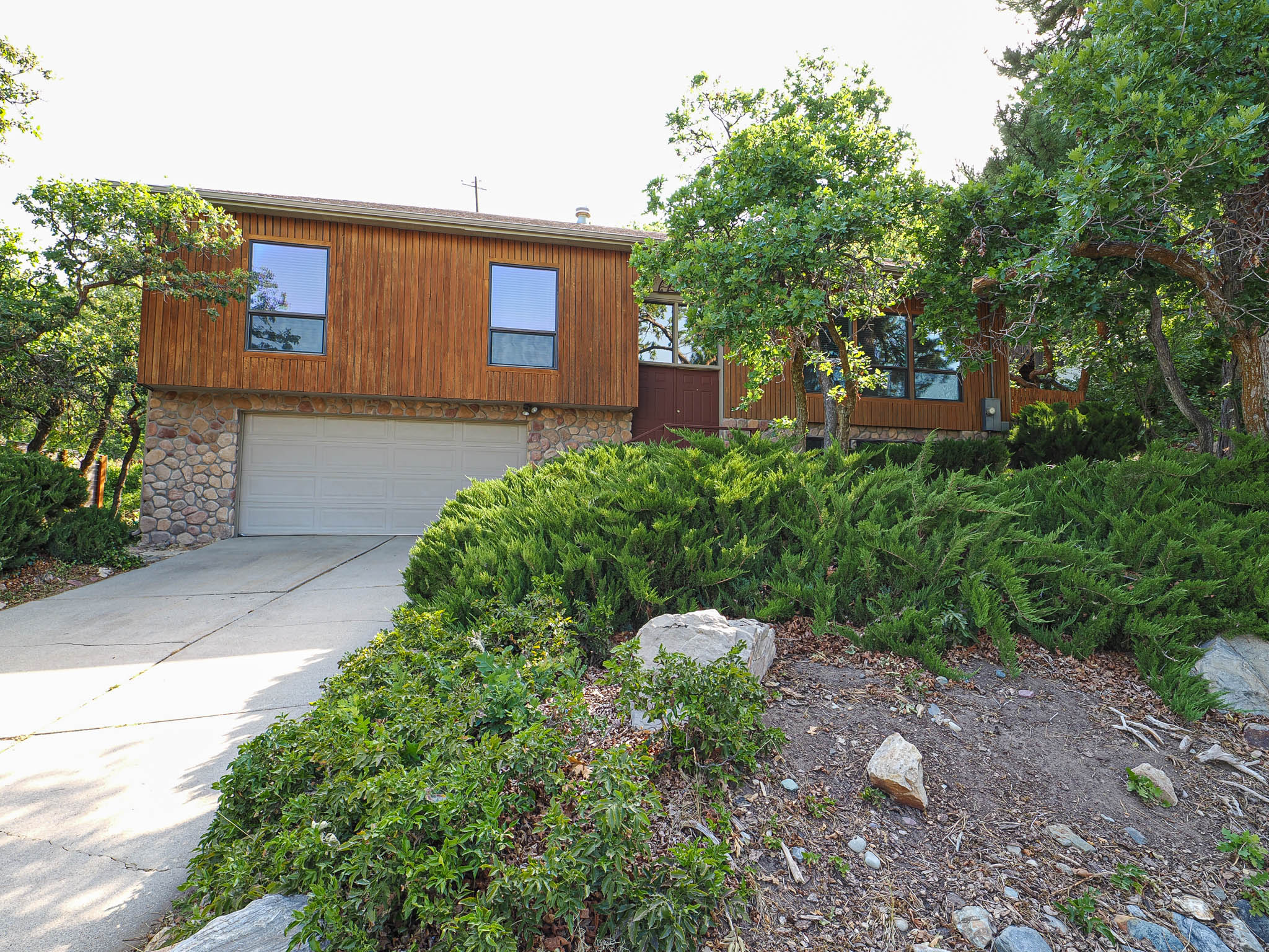 Wood-sided residence featuring a stone facade and an integrated two-car garage