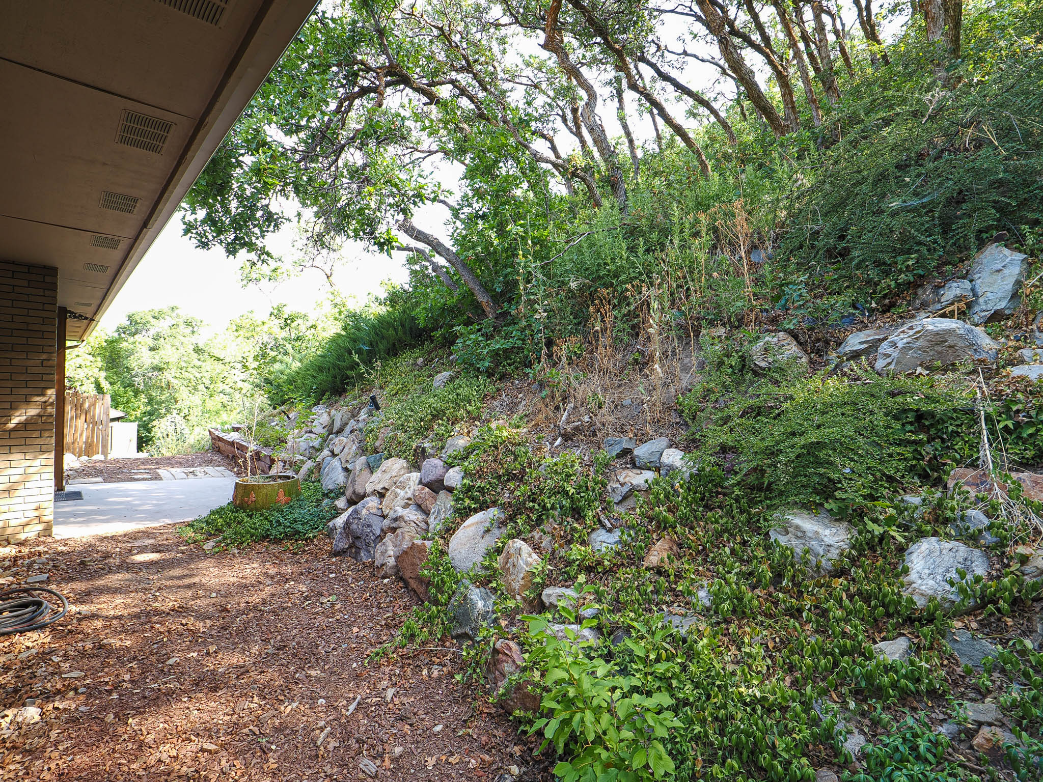 Terraced landscaping featuring natural stone retaining walls and mature trees