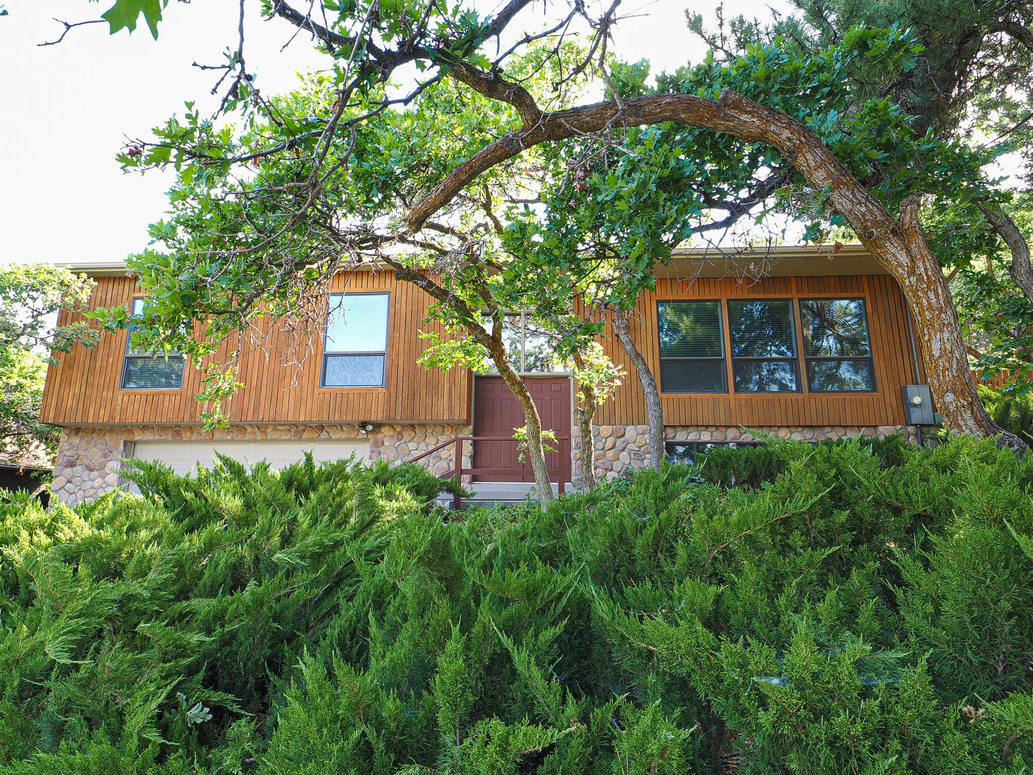Split-level property featuring wood siding and stone accents