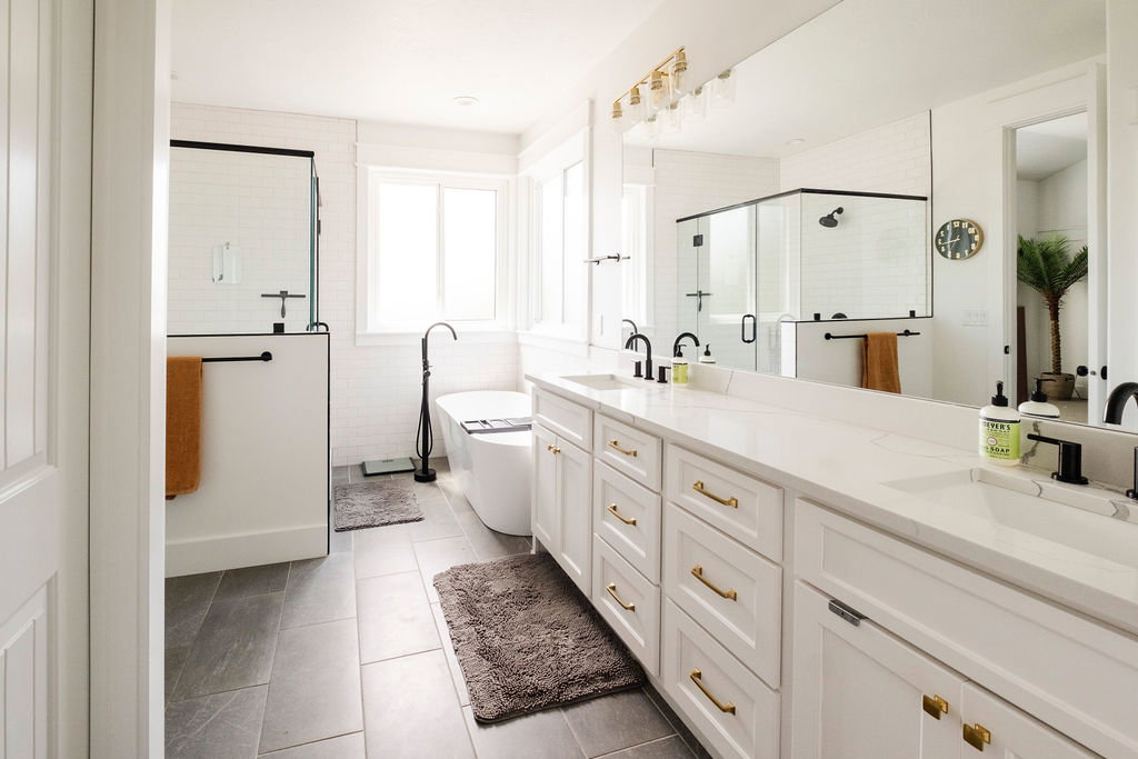Dual vanity with white cabinetry, gold-finish hardware, and a light-toned countertop