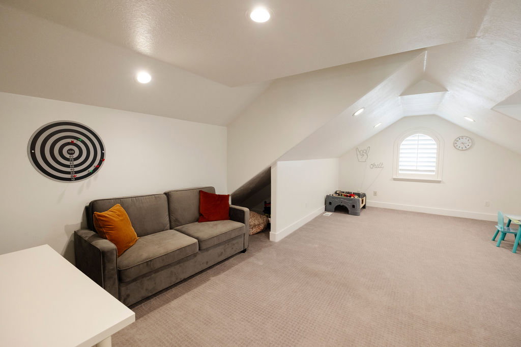 Spacious bonus room featuring an arched window with louvered shutters, sloped ceilings, recessed lighting, and neutral-toned carpeting