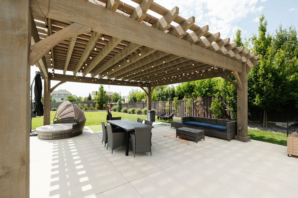 Expansive patio area featuring a substantial wooden pergola with string lighting