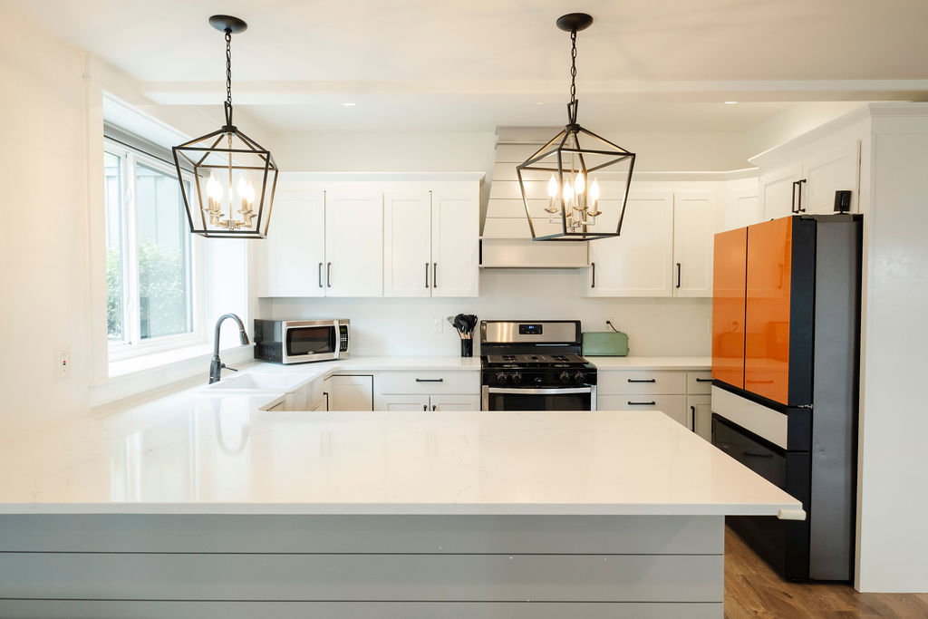 Kitchen featuring a large central island with a quartz countertop, white shaker-style cabinetry, stainless steel range, and a shiplap-accented range hood