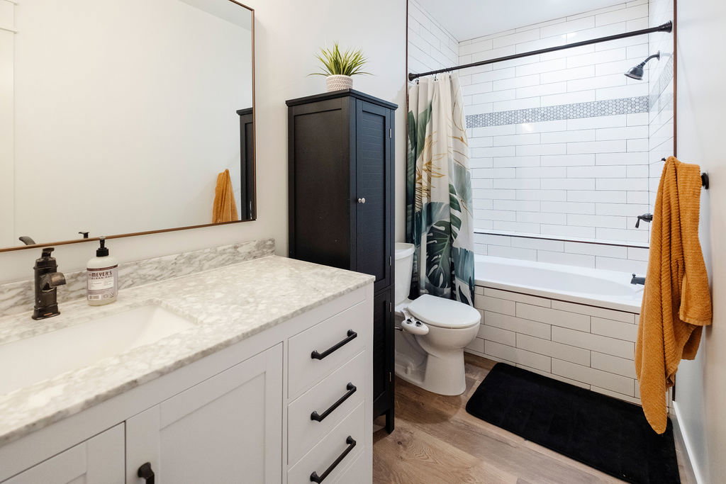 Bathroom featuring a white vanity with a stone countertop, an undermount sink, and black hardware