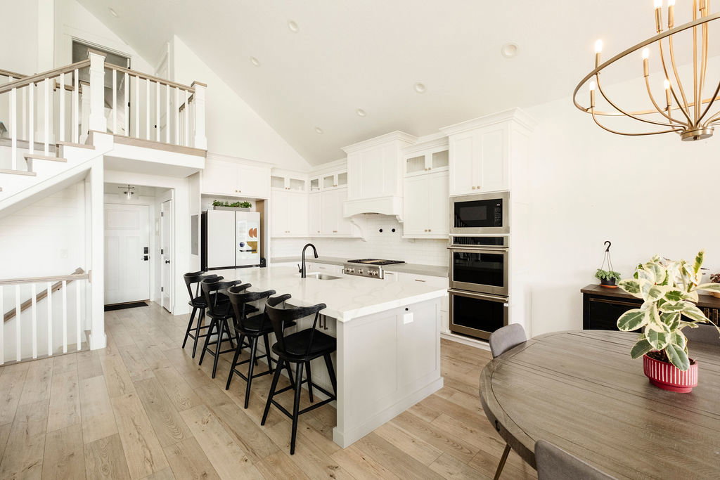 Gourmet kitchen featuring a large island with seating, stainless steel appliances, white cabinetry, and wood-finish flooring
