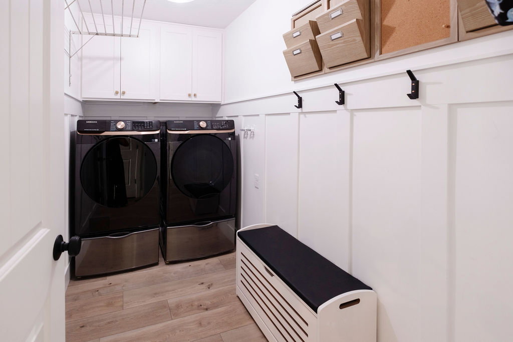 Laundry area featuring light wood-finish flooring and white board and batten wall paneling
