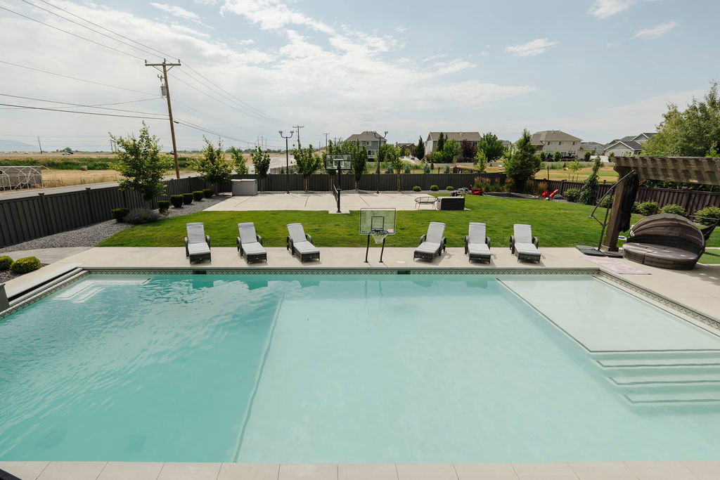 Outdoor swimming pool with integrated sun shelf and steps, surrounded by concrete decking