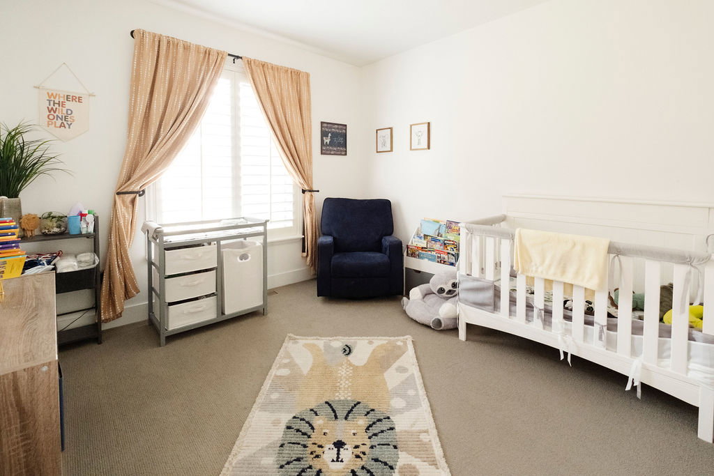 Carpeted room featuring a large window with white plantation shutters and light-colored drapes