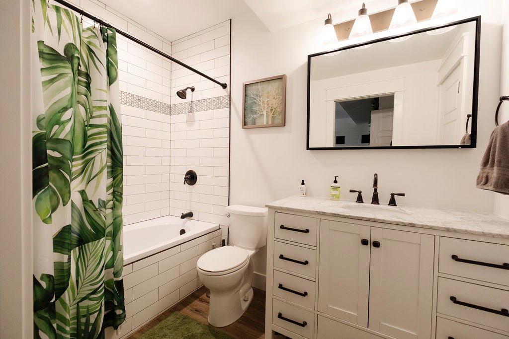 Bathroom featuring a white subway-tiled tub/shower combination with a decorative mosaic accent stripe