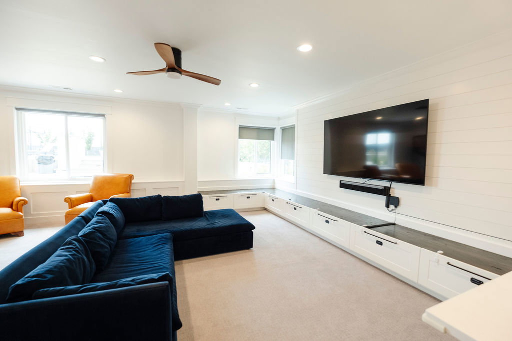 Recreation space featuring a wall-mounted television, an extensive built-in media console with cabinet storage, and shiplap accent wall