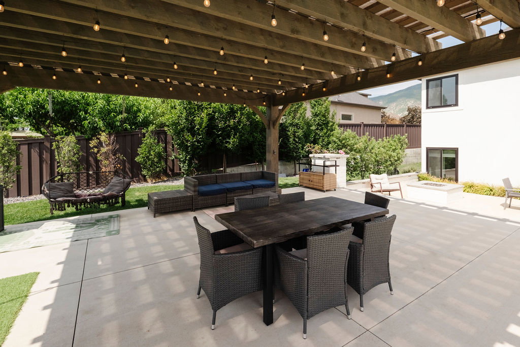 Expansive concrete patio featuring a wood pergola with string lighting