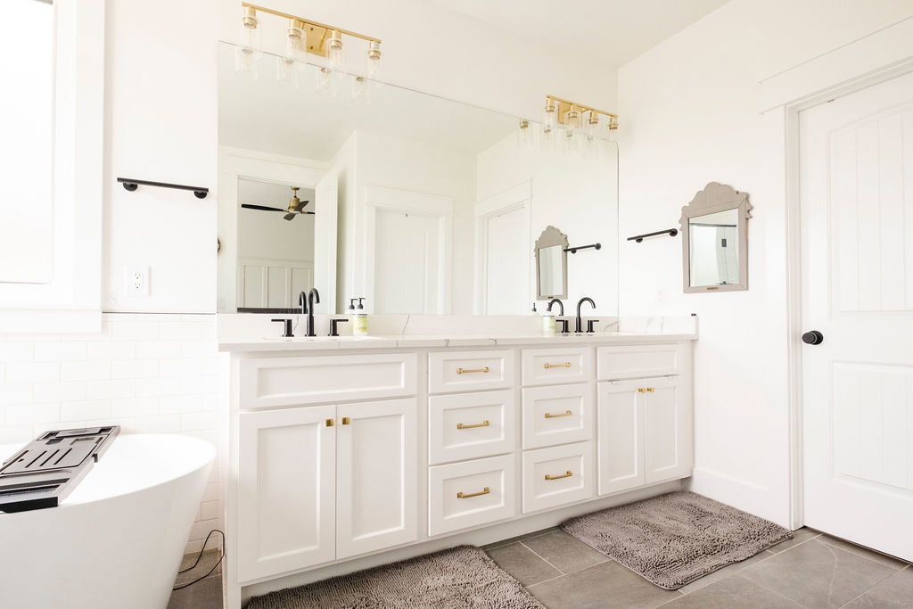 Dual vanity with white cabinetry, gold-finish hardware, and a stone countertop