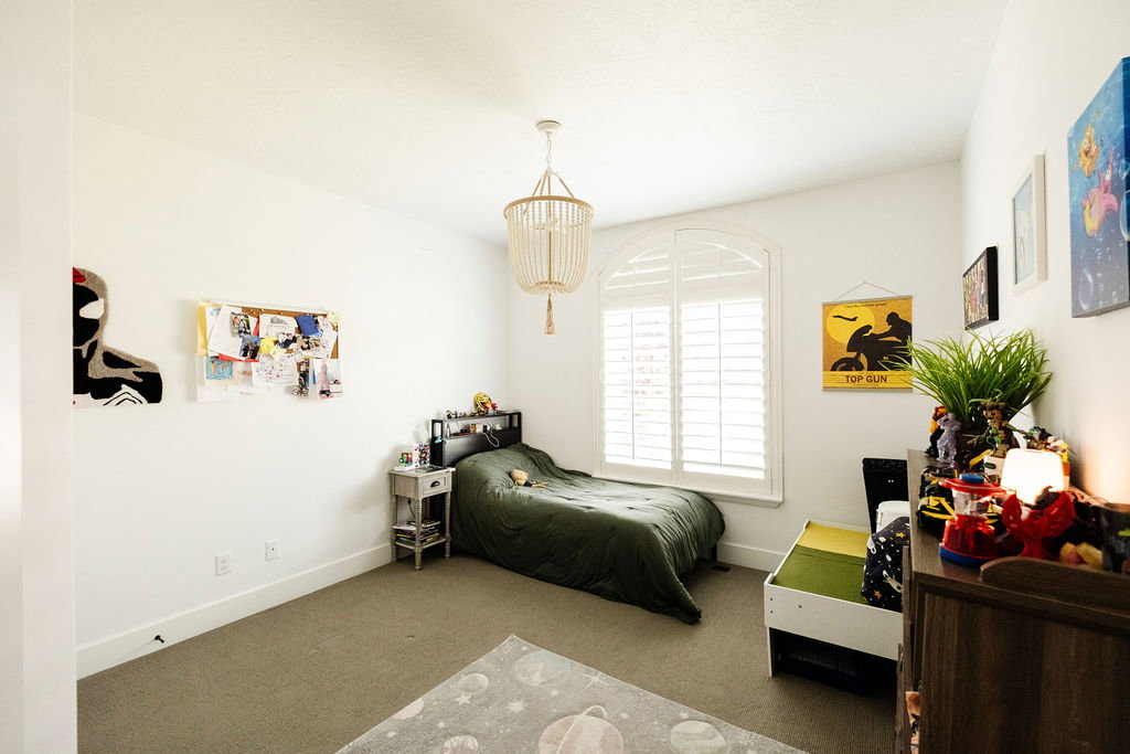 Room featuring an arched window with plantation shutters, neutral carpet, and a decorative ceiling light fixture