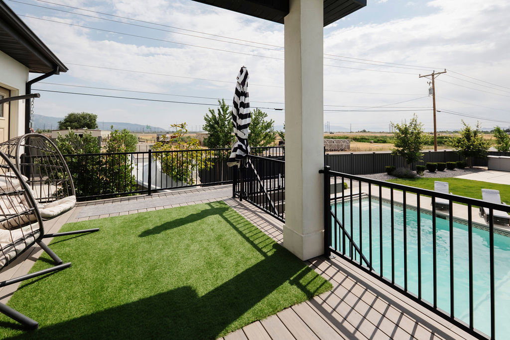Expansive deck with composite wood-finish flooring, a swimming pool, and a dedicated artificial turf area