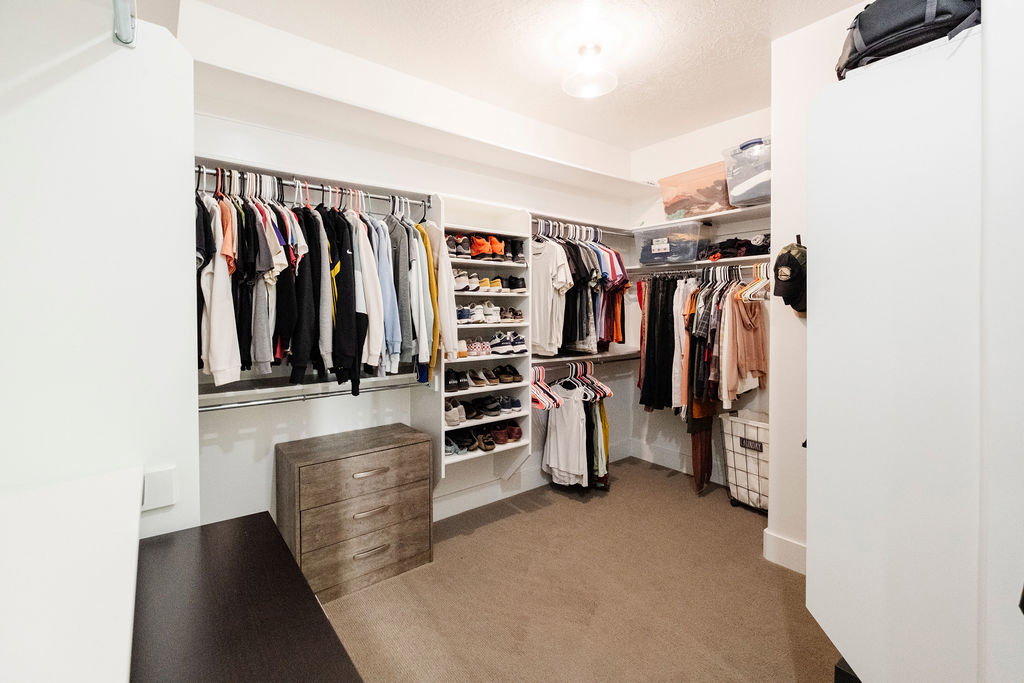 Walk-in closet featuring built-in shelving, clothing rods, a three-drawer wood-finish dresser, and carpet flooring