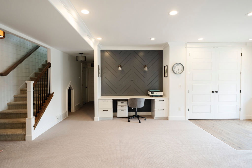 Integrated office nook featuring built-in cabinetry and a herringbone-patterned accent wall