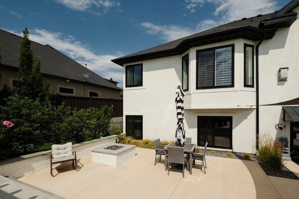 Expansive concrete patio area featuring a built-in fire pit with stone-look surround