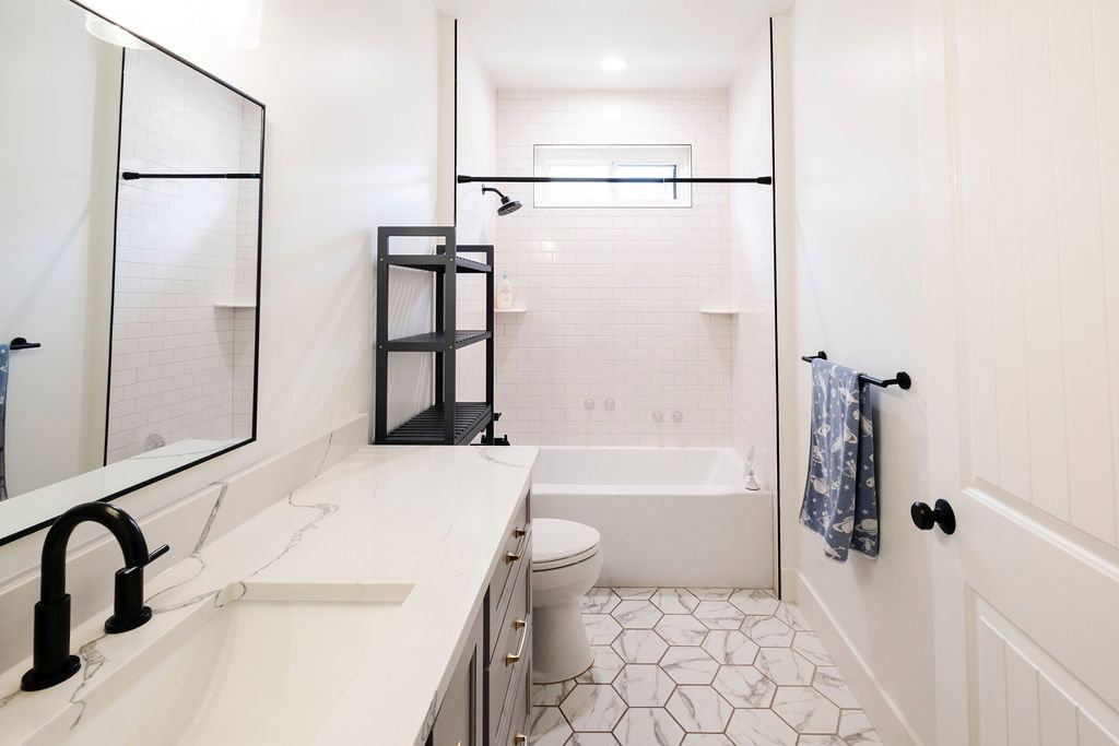 Bathroom featuring a white subway tile shower surround with a built-in niche, a white tub, and a window for natural light