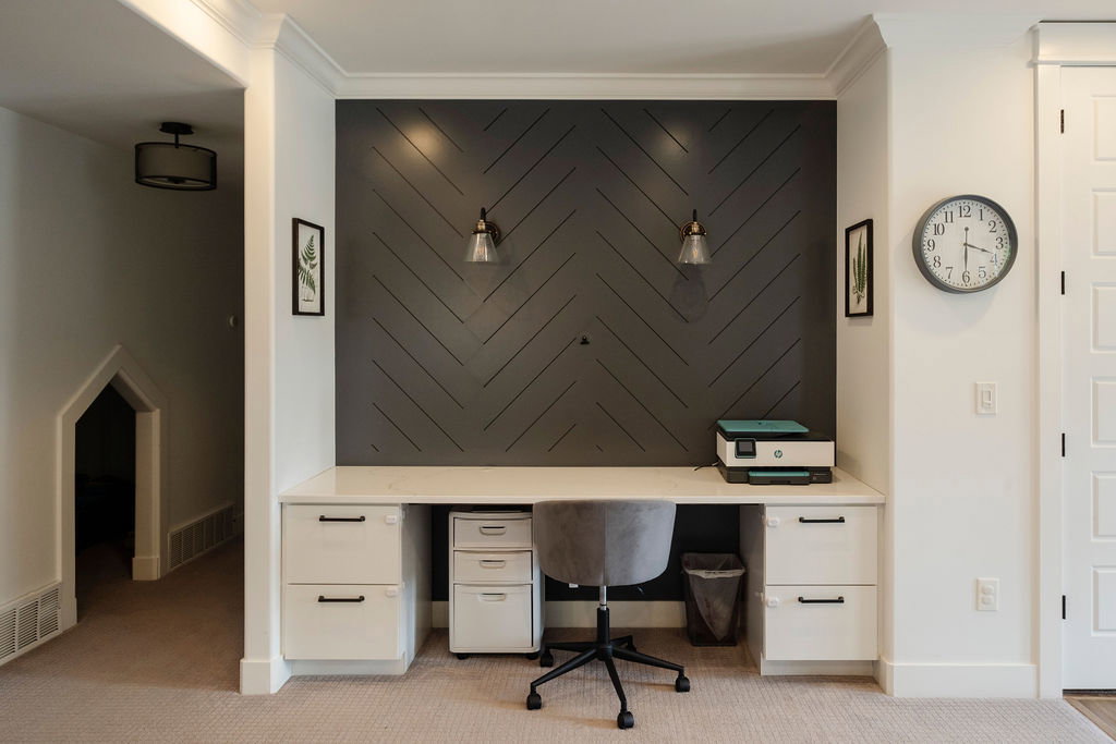Built-in desk featuring a light-colored countertop and integrated white cabinetry with black hardware