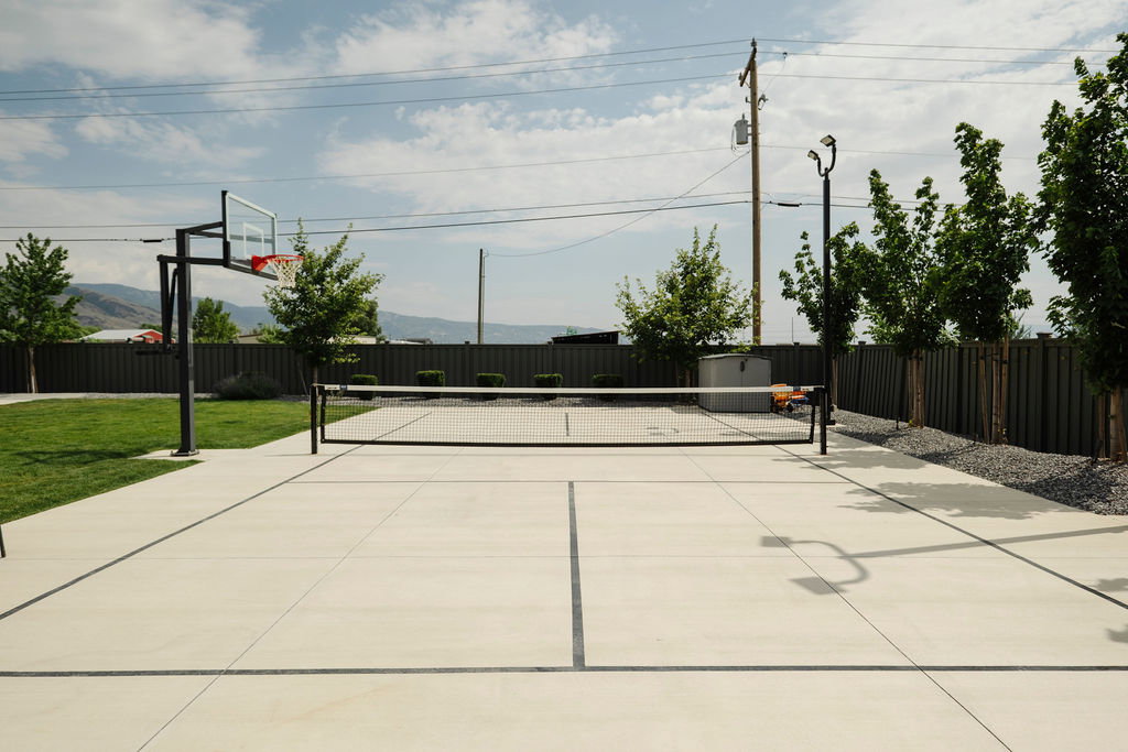 Concrete multi-sport court featuring a basketball hoop and net