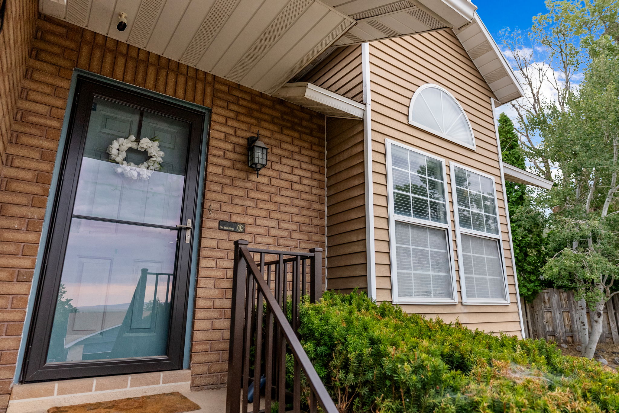 Brick and siding exterior with a storm door, an arched transom window, and a built-in outdoor light fixture