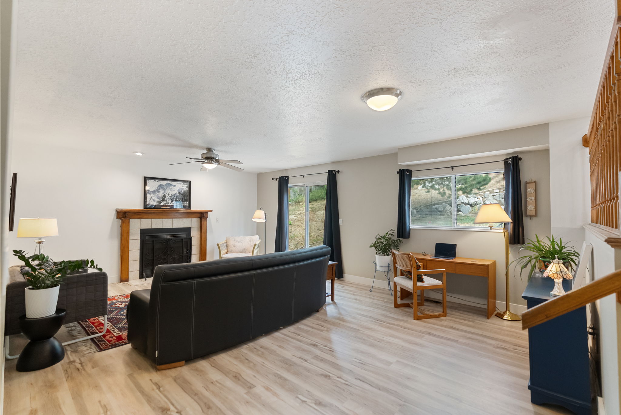 Open concept living area featuring wood-finish flooring, a fireplace with a wood mantle and tile surround, and multiple windows