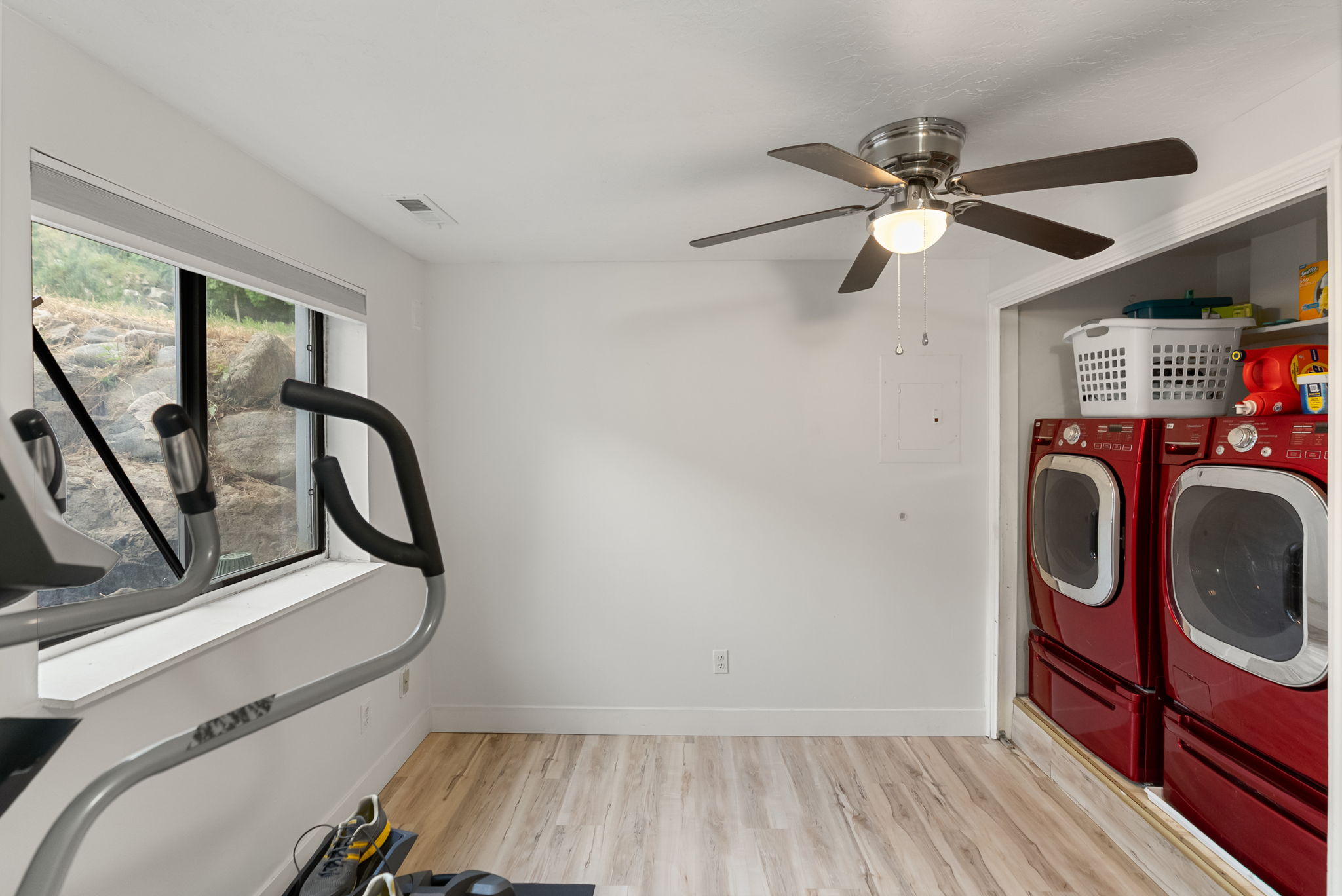 Versatile room featuring wood-finish flooring, a contemporary window, and a ceiling fan with integrated lighting