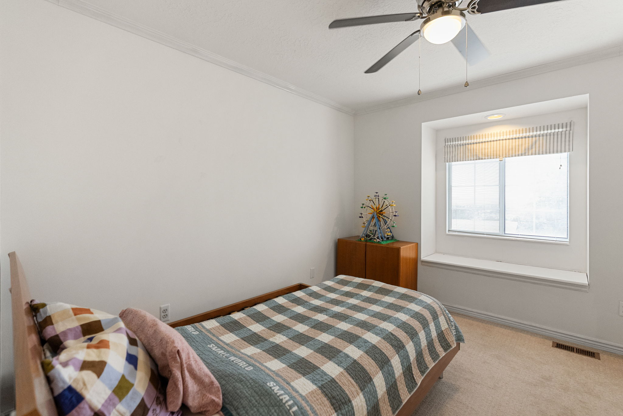 Carpeted room featuring a ceiling fan with integrated lighting, a recessed window with blinds, and a built-in window seat