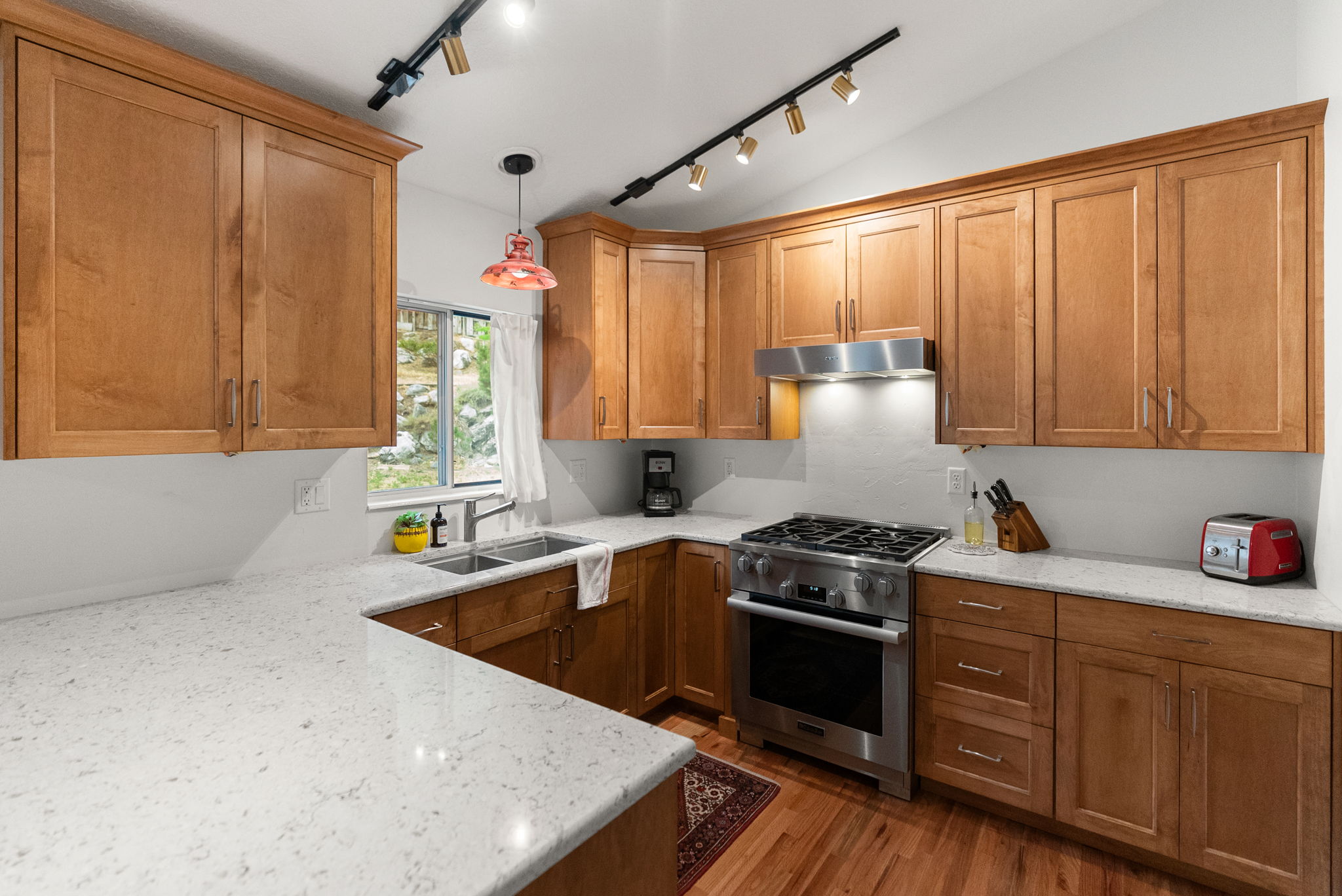 Kitchen featuring light wood cabinetry, light-toned countertops, stainless steel appliances, and wood-finish flooring