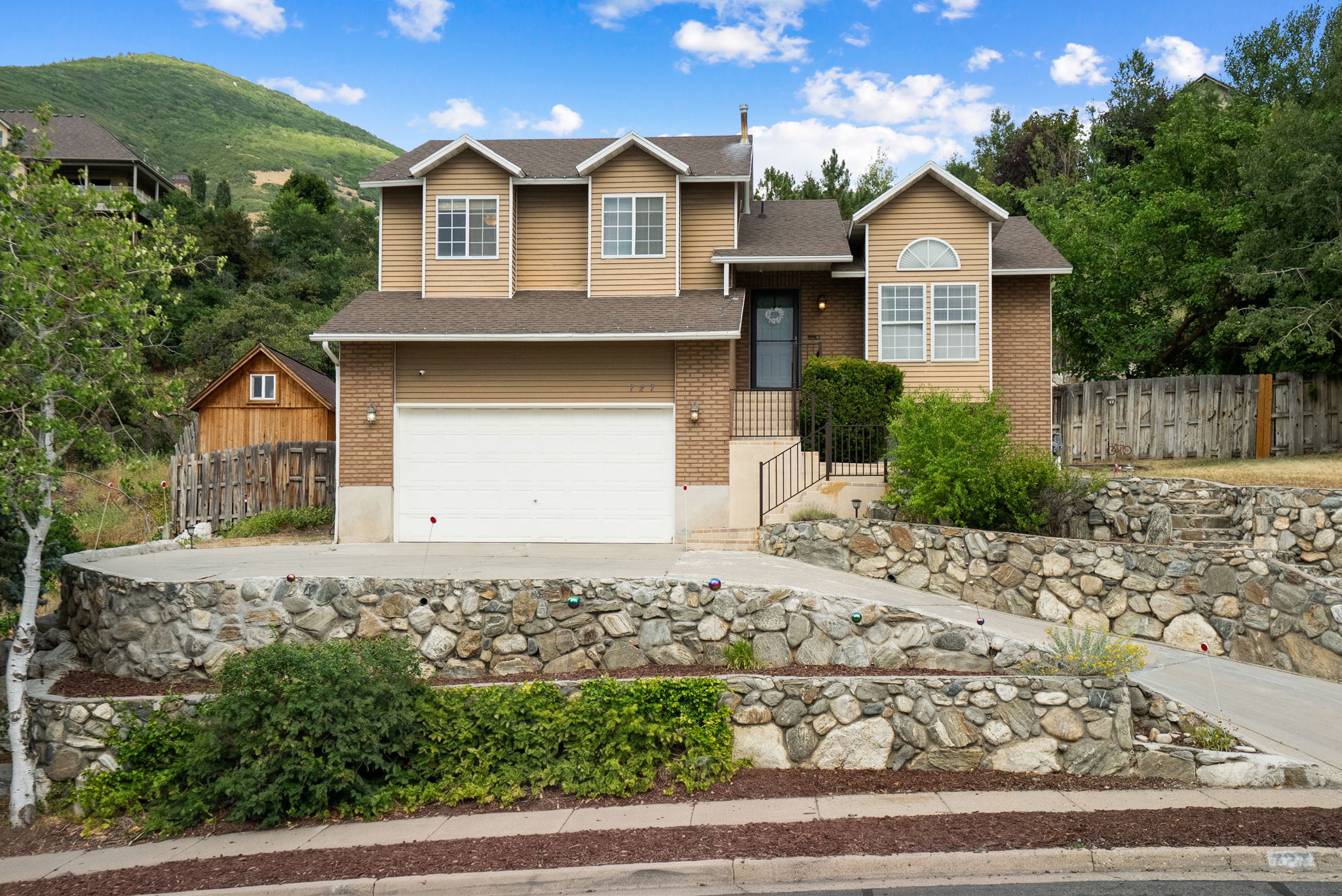 Two-story residence featuring a two-car garage and a stone retaining wall