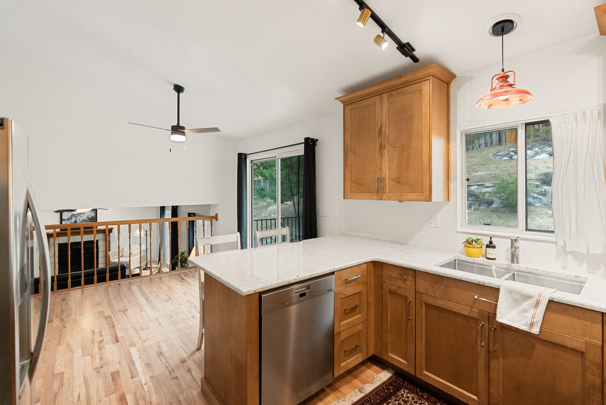 Kitchen featuring light wood cabinetry, white stone countertops, stainless steel appliances, a double basin sink, and a window with exterior landscaping
