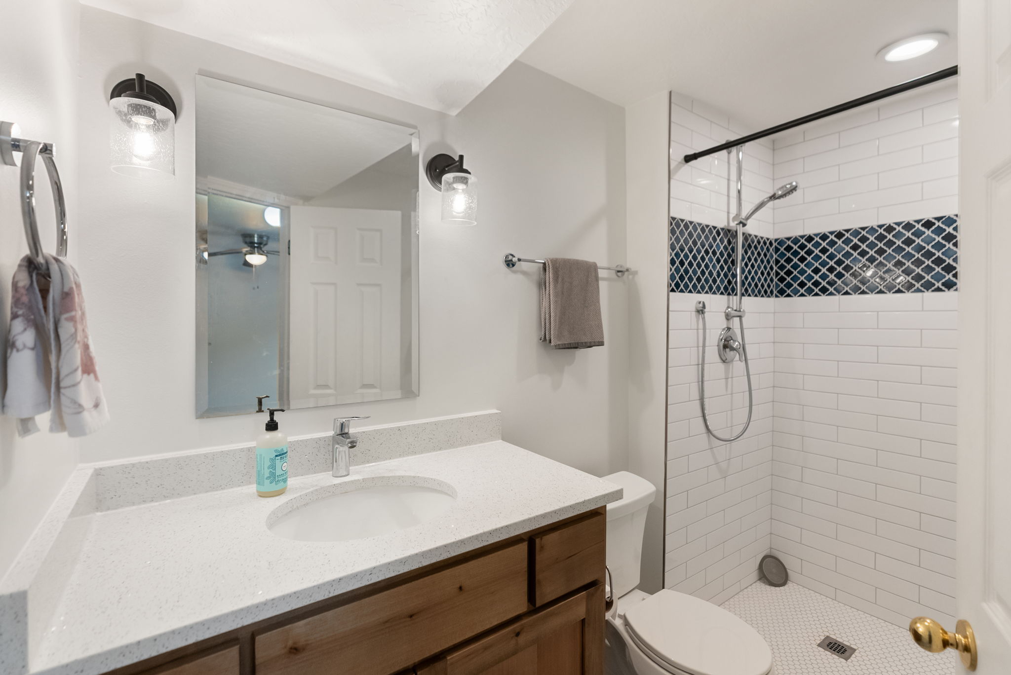 Contemporary bathroom featuring a walk-in shower with subway tile and a decorative mosaic accent band
