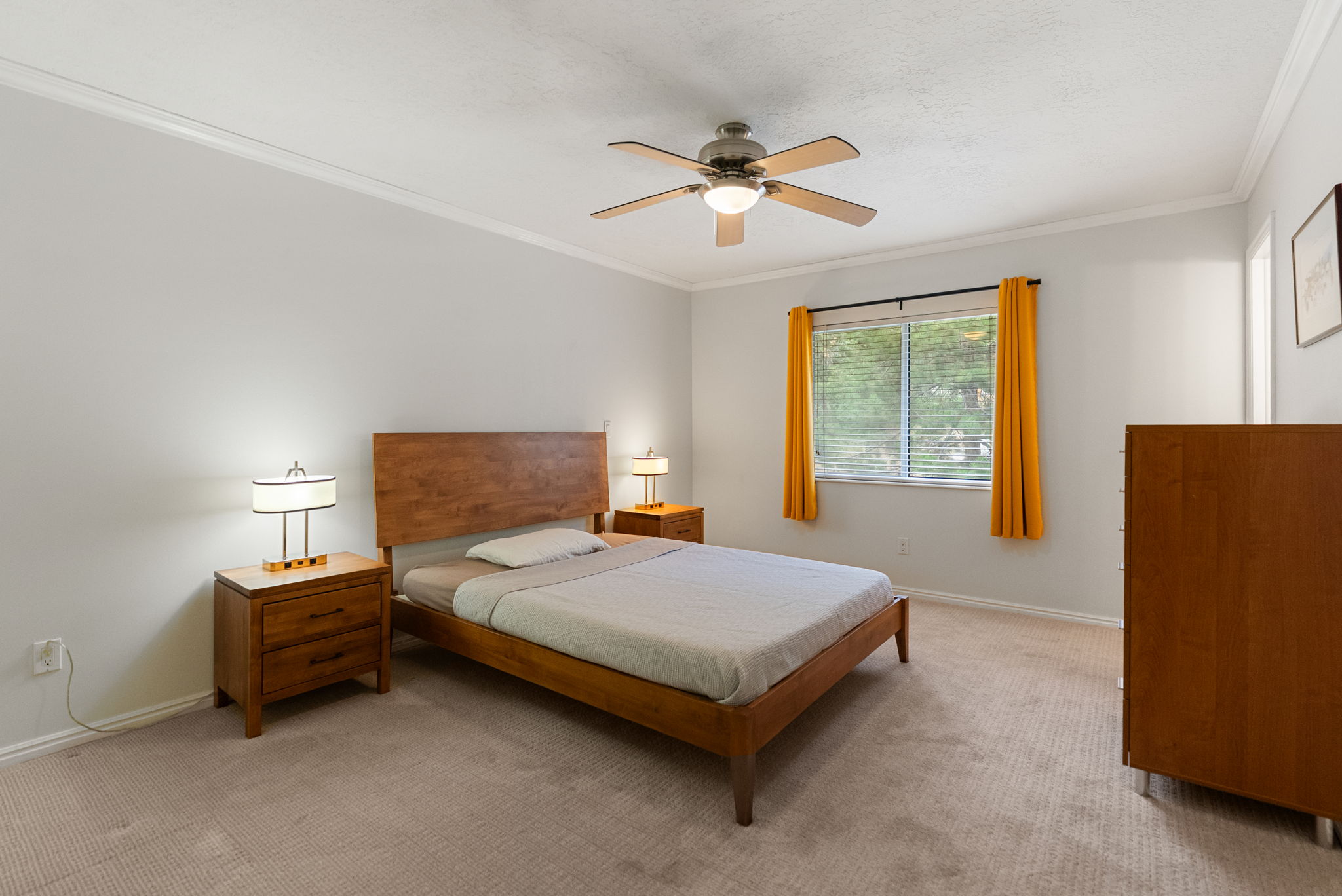 Spacious interior room featuring light-colored walls, crown molding, and neutral-toned carpeting