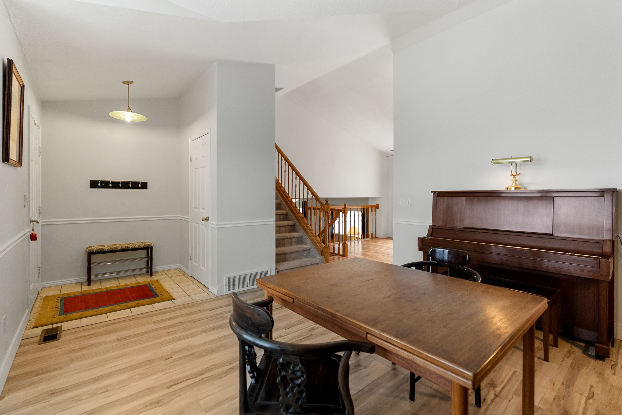 Entryway with wood-finish flooring, a white paneled door, and a staircase with wood railings