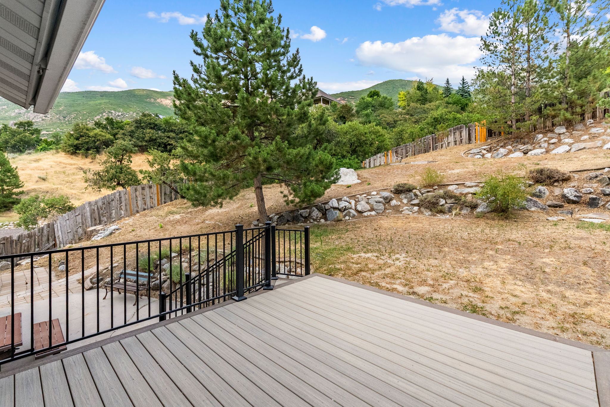 Expansive outdoor deck with composite decking, black metal railing, and a patio area below