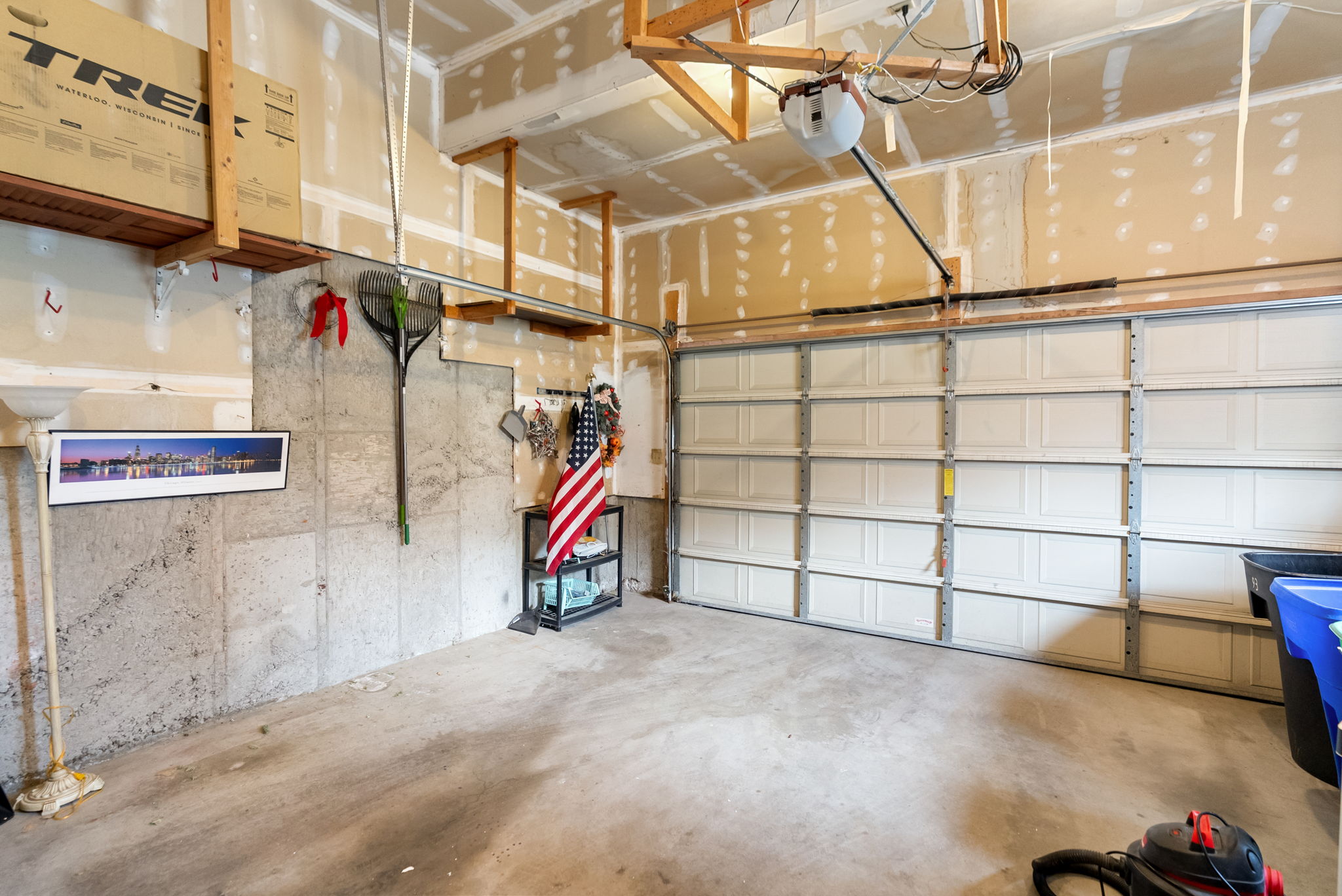 Garage featuring a sectional overhead door, exposed concrete foundation wall, overhead storage racks, and an automatic garage door opener
