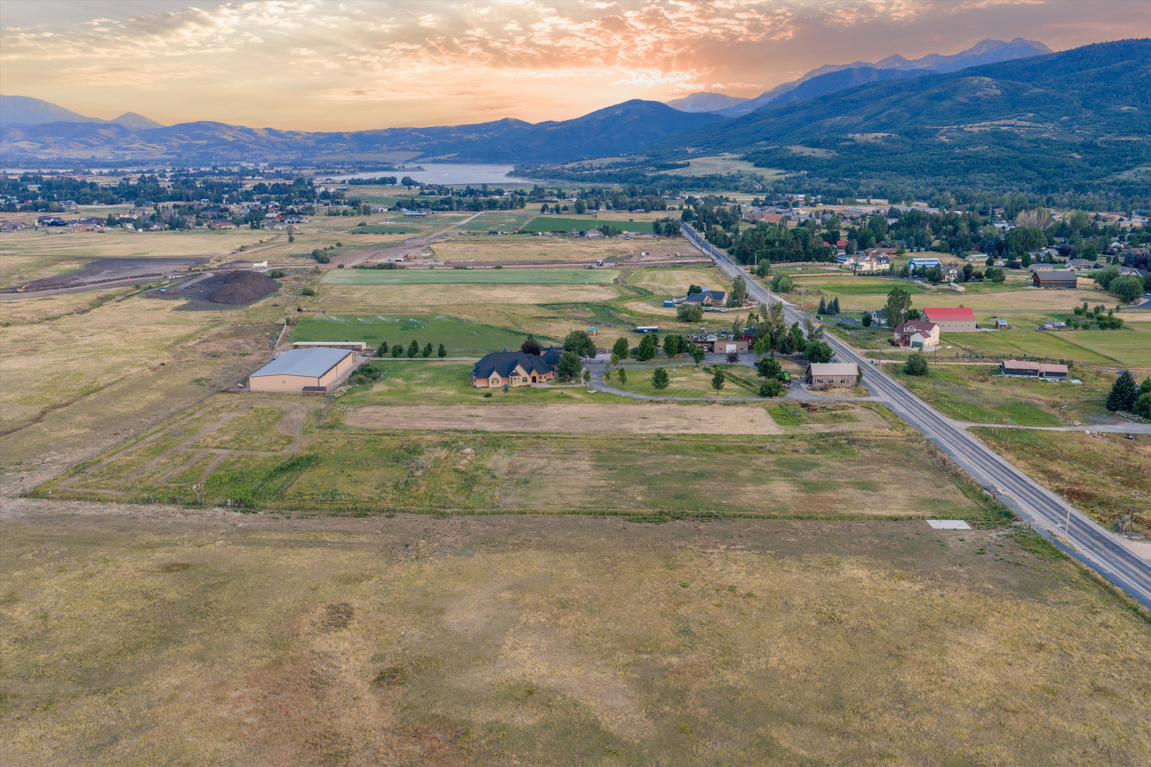 Expansive rural property featuring a large residence with a circular driveway, substantial outbuilding, and significant undeveloped land