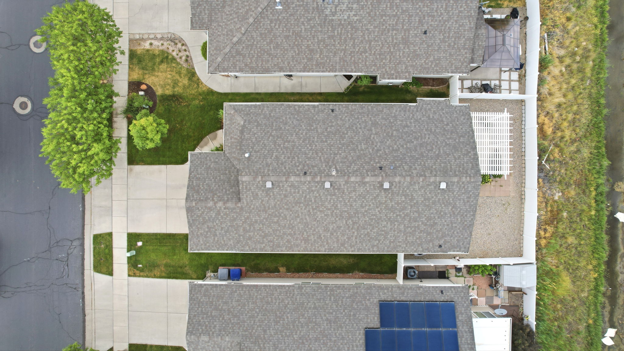 Shingled roofline with a gravel side yard and white pergola