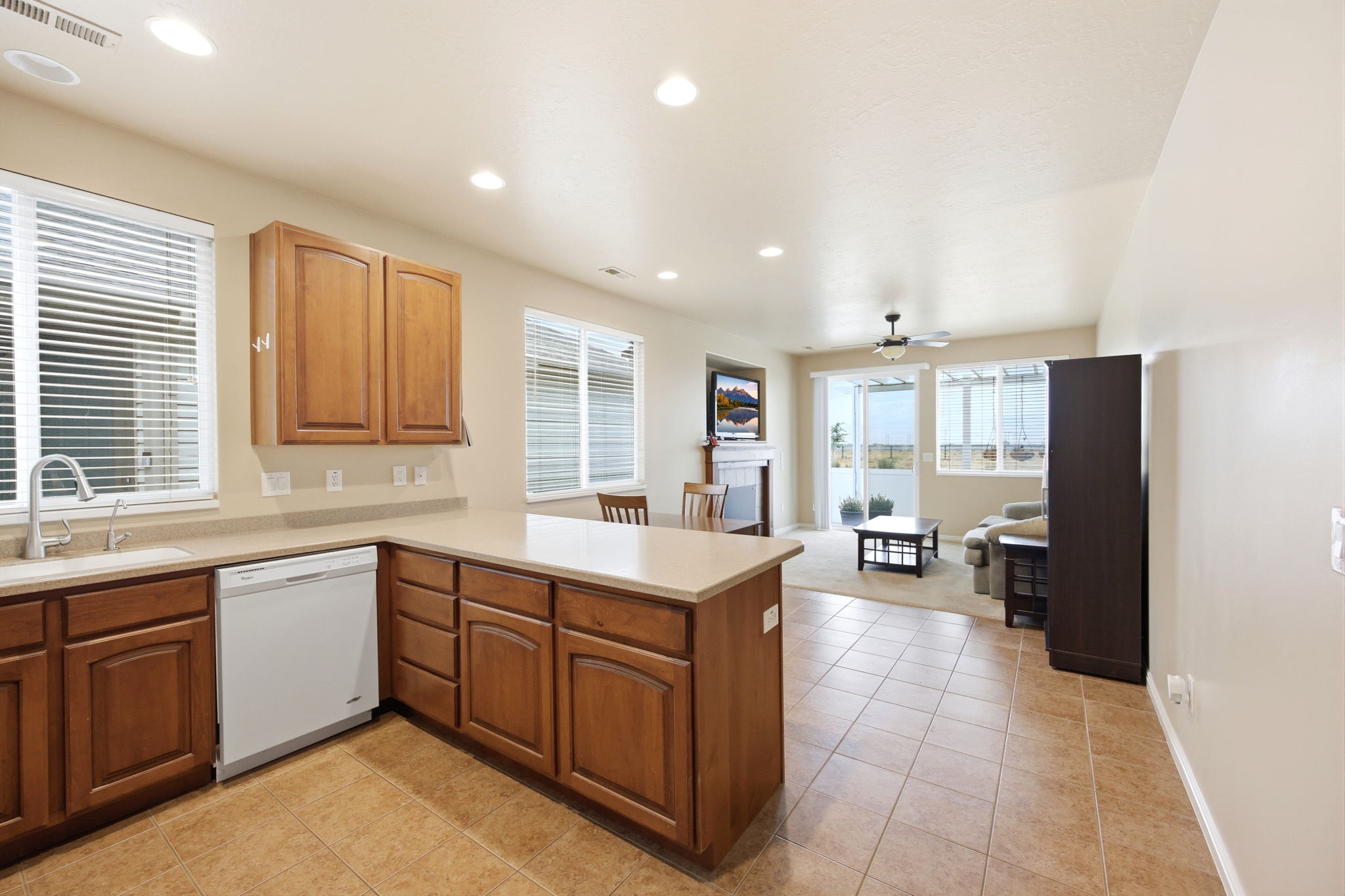 Open concept kitchen featuring warm wood cabinetry, light-toned countertops, and tile flooring
