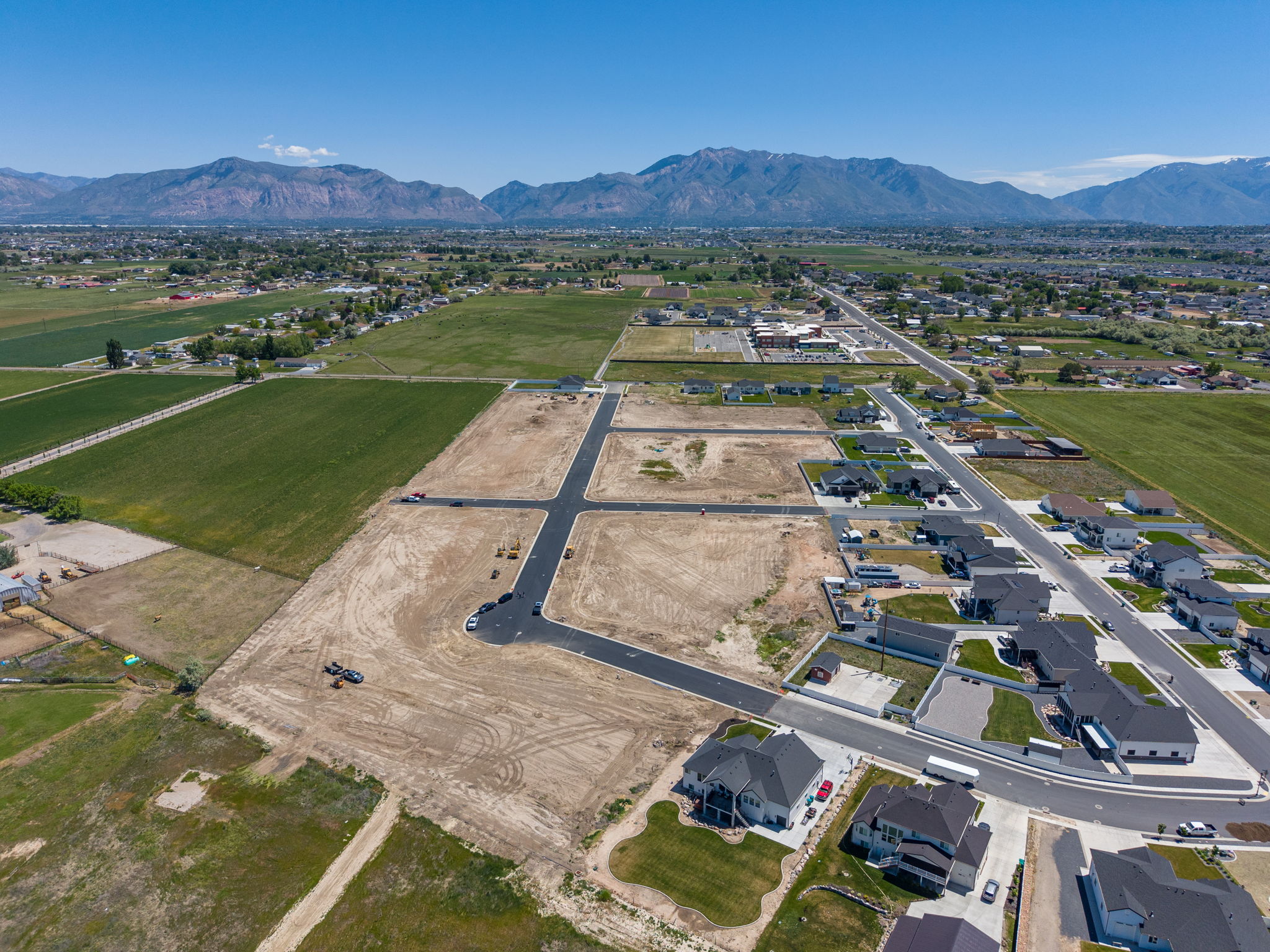 Aerial perspective showcasing a developing residential area with paved streets and surrounding green fields