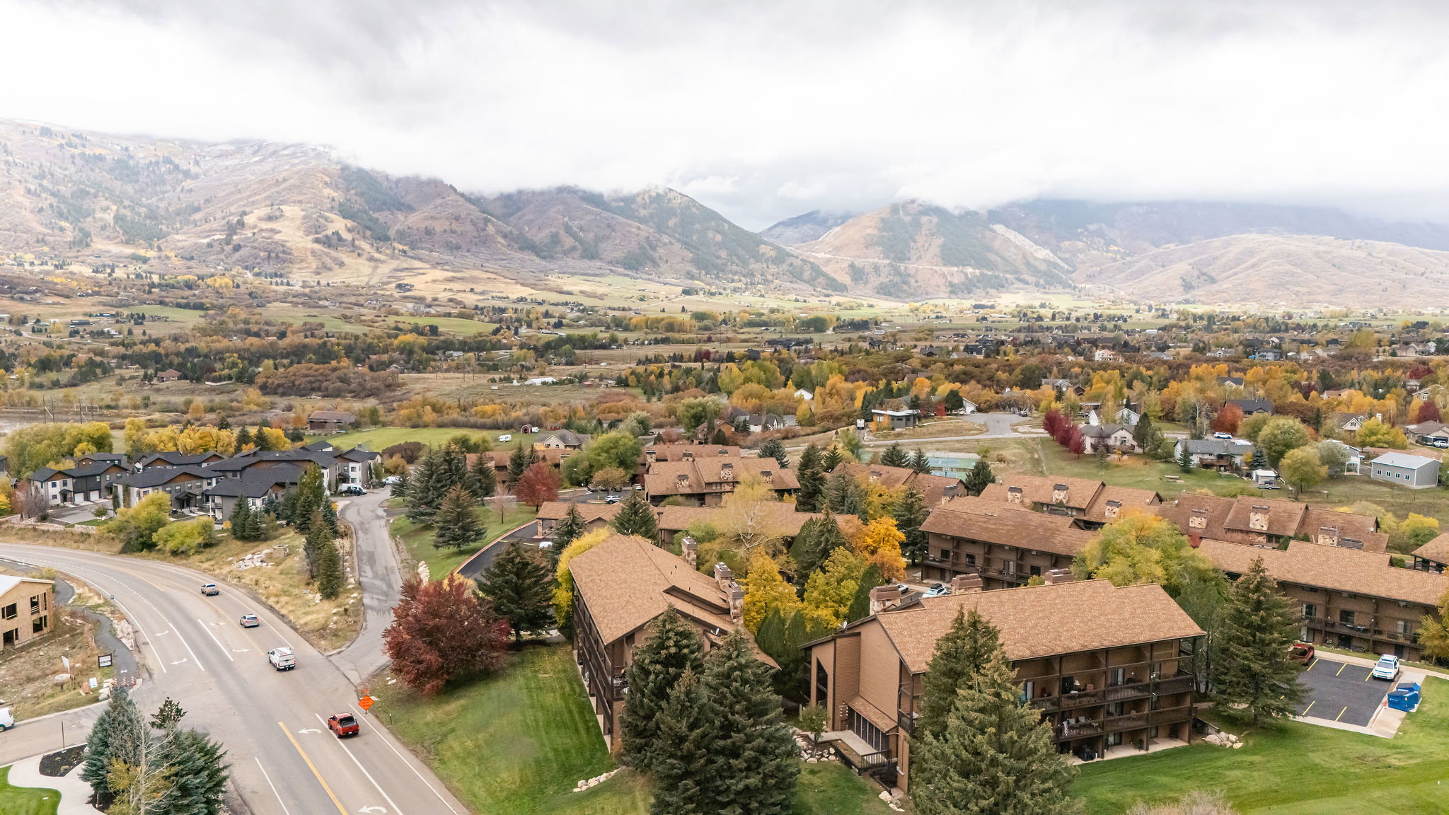 Aerial perspective showcasing multiple residential structures, a curved roadway, and distant mountains