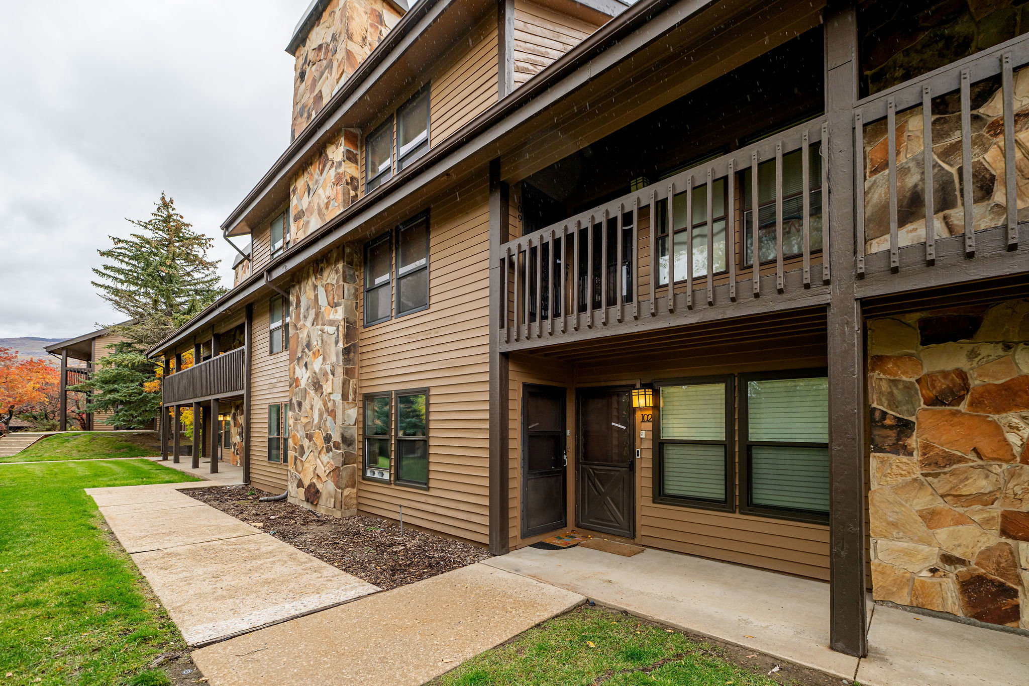 Multi-level exterior featuring natural stone accents, horizontal siding, and a private balcony