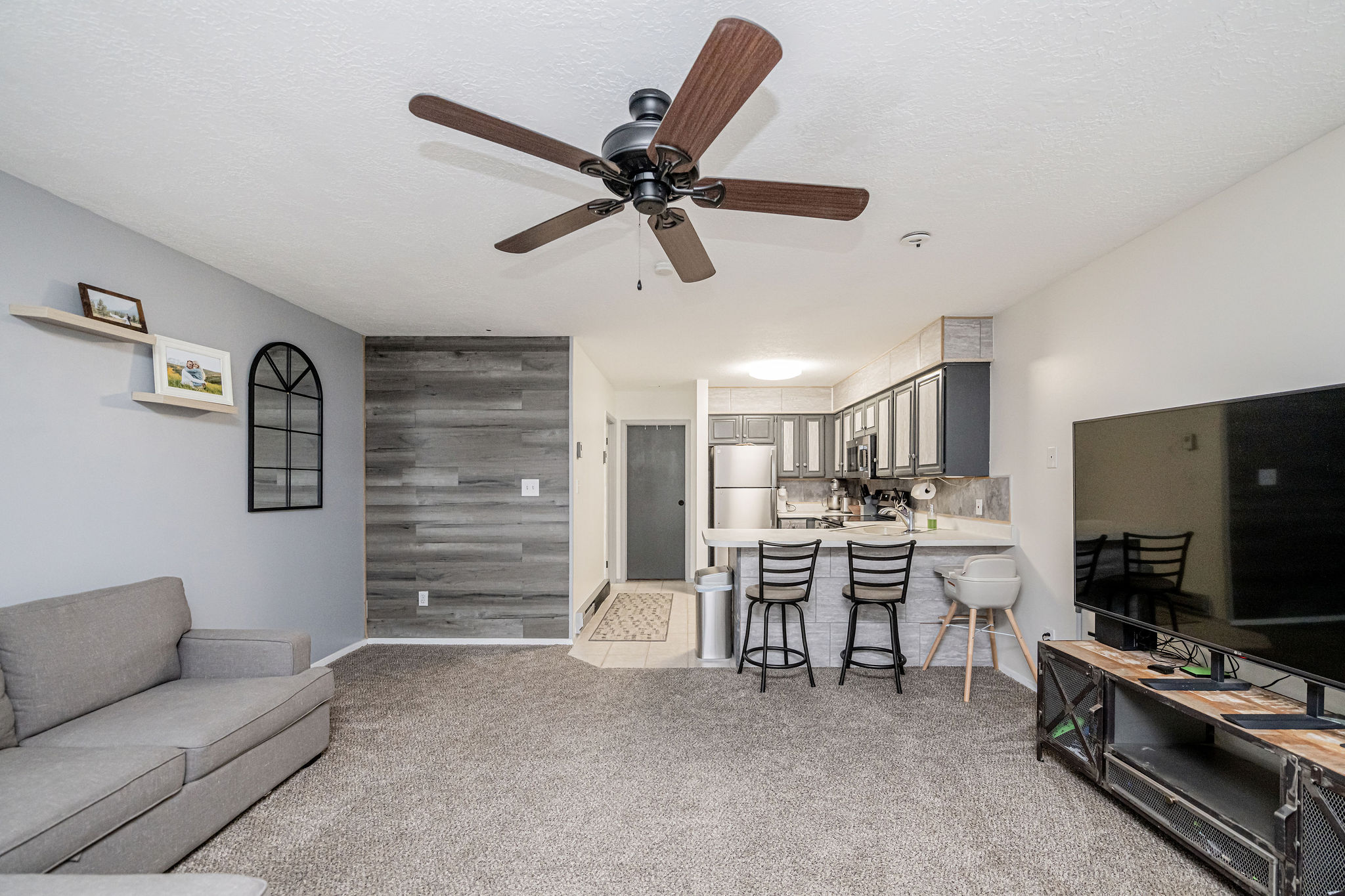 Open-concept living area with a wood-finish accent wall